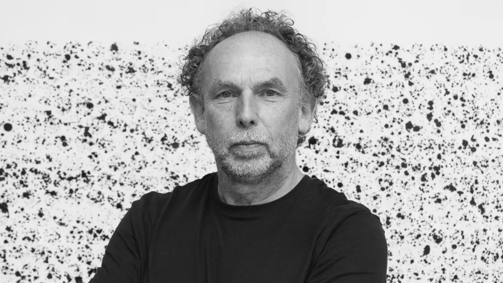 A black and white image showing Richard, who wears a black t-shirt, looking at the camera.