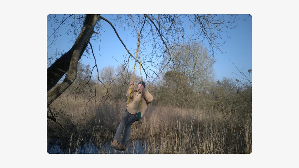 An older man rides a rope swing above a river with trees behind him. Credit: Russell Sparkes.